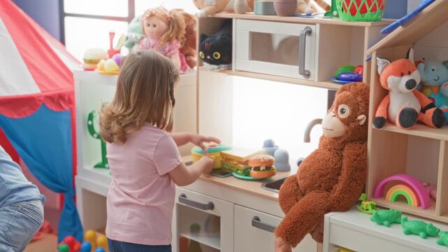 Little girl reaches for a toy burger on a play kitchen counter in a bright playroom filled with stuffed animals and a tent; imagination joy friendship.