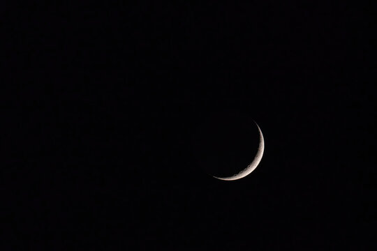 Waxing crescent moon with visible craters against dark night sky