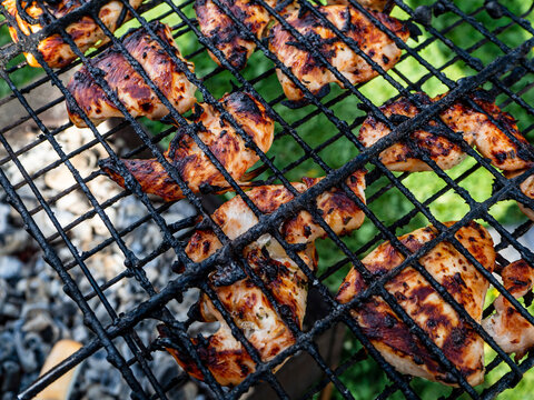 Background with chicken meat fried on a grill over coals. Close-up.
