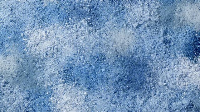 Overhead slow-motion frame captures blue powder smears arranged in rows and columns bursting as if smashed from behind