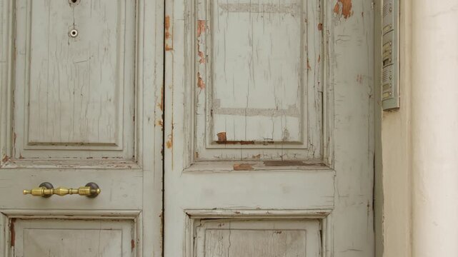 Weathered white wooden door with peeling paint and worn textures in Ostuni, Brindisi, Puglia, Italy, showcasing traditional architecture, craftsmanship and Mediterranean residential character, static