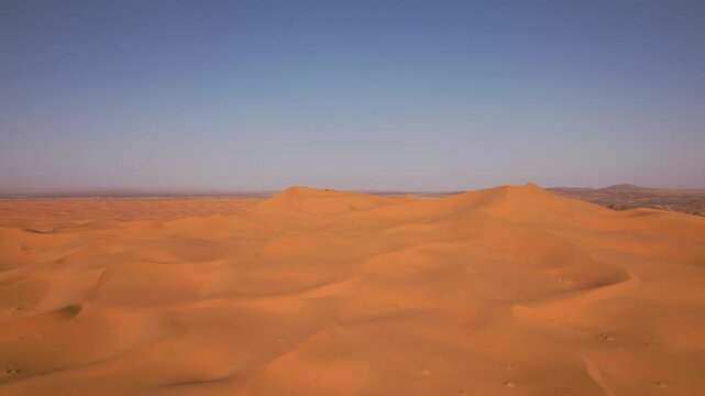 Erg Chebbi stretches across Merzouga, Errachidia Province, Dr&acirc;a-Tafilalet, Morocco, revealing an immense sand sea shaped by aeolian processes and wind-driven dune migration, forward flyover ascent