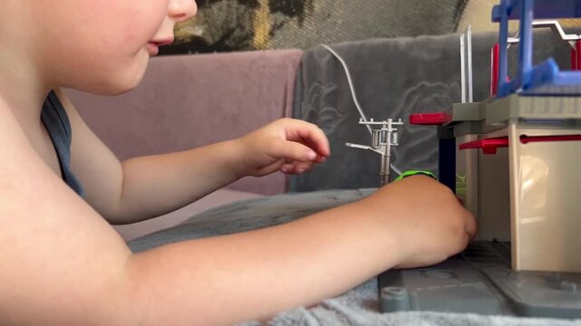 A young boy focuses on playing with colorful toy cars and a multi-level garage playset on a grey surface.