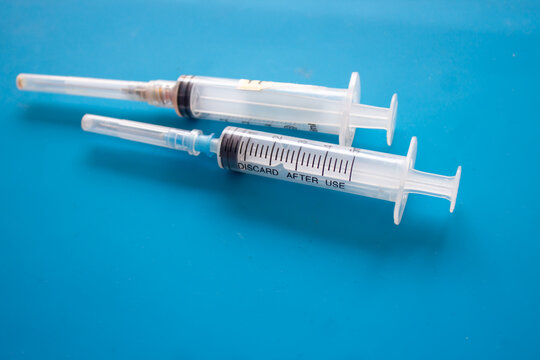 Used Disposable Syringes on Blue Background with Copy Space &ndash; Healthcare and Medical Waste Concept
