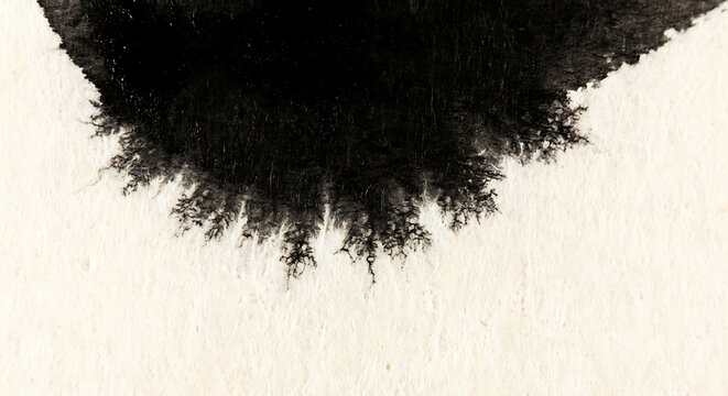 Abstract black ink bleeding on textured white paper background