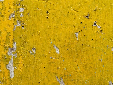 Texture of peeling bright yellow paint on an old wall