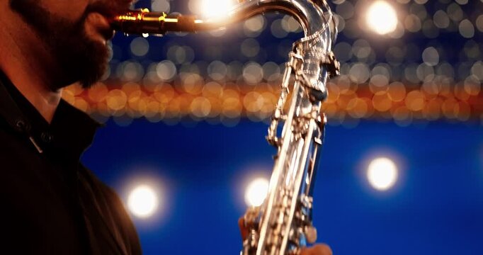 Male saxophonist playing tenor sax on stage with warm bokeh lights