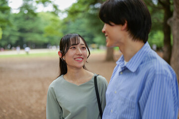 Obraz premium 新緑の公園で話をする笑顔のカップル