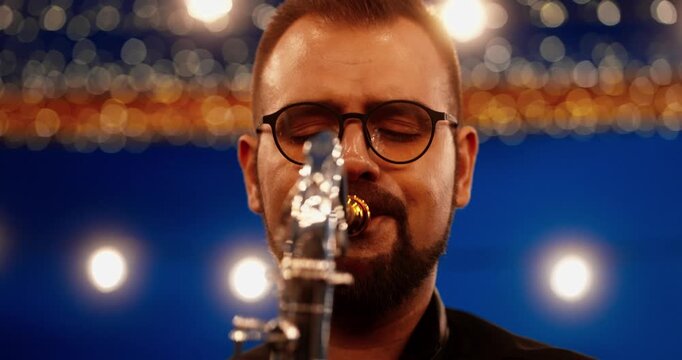 Close-up of male saxophonist performing under warm string lights