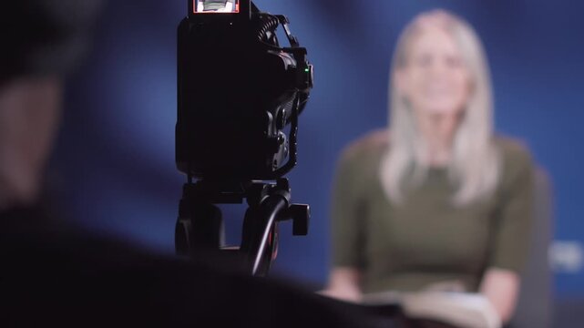 Close up focus of modern professional camera filming blonde woman vlogger sharing encouraging Bible verses, female Christian content creator talking to viewers, recording faith-based video tutorial on
