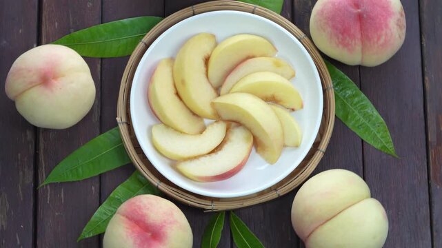 White Peaches with leaves and Slice of  Peach on white dish, Fresh White Peach on wooden basket in wooden Background.