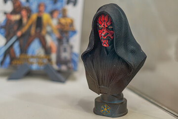 Fototapeta premium Close-up image of a black and red Darth Moul bust from Star Wars, against a light gray background Two Star Wars books Princess Leia, C-3PO nearby Focused lighti - Kyiv, Ukraine - September 27, 2025