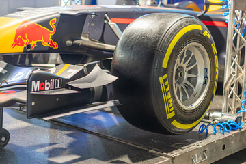Fototapeta premium Red Bull Formula 1 car part on metal platform, vibrant red and black body with yellow tire accents, contrasting blue Red Bull banner - Kyiv, Ukraine - June 7, 2025