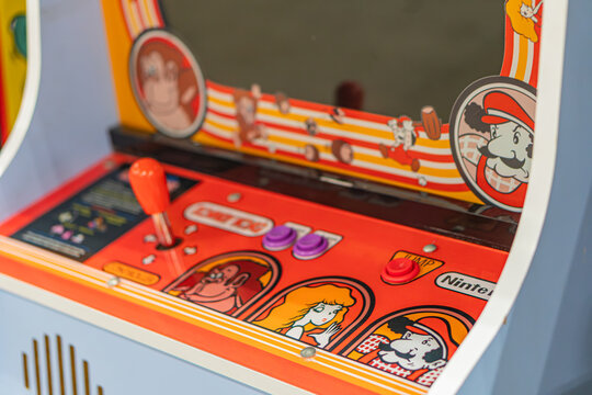 Vibrant arcade setting with focus on a red and yellow Nintendo-themed pinball machine, featuring cartoon characters illustrations, multiple control buttons, speakers - Kyiv, Ukraine - June 7, 2025