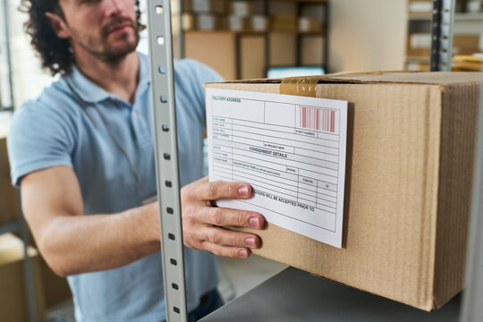 Young man handling labeled parcel at order pickup point, managing inventory and delivery workflow. Ideal for logistics, ecommerce fulfillment, shipping service marketing