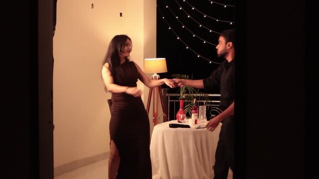 Romantic couple performing partner dance during intimate candlelight dinner date celebration