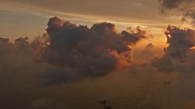 Dramatic sunset clouds glowing above ocean waters during evening light, aerial pan right
