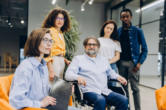Diverse business team collaborating in modern office setting. middle aged man sitting in wheelchair