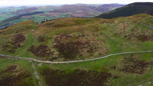 Lone Hiker Walking Gravel Trail Through Slieve Meen Mountains with Sheep on a Cloudy Day