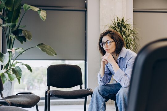 Sad upset woman thinking, waiting in office hallway before meeting