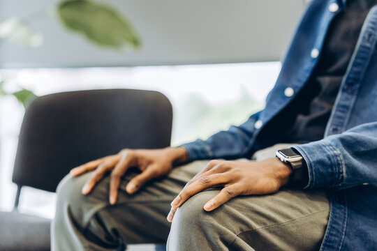 Man waiting patiently with hands resting on lap selective focus on hands