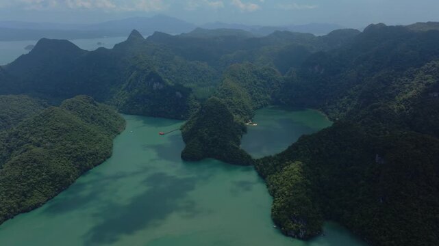 A smooth 4K slow motion aerial sequence flying over the iconic Dayang Bunting Lake, highlighting the lush green scenery and unique mountain formations in Malaysia.