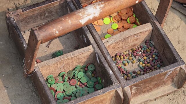 High angle shot of a wooden token box used for tracking manual labor value at a Bangladesh brickyard. Documents variable piece-rate wage systems, traditional accounting, and local economics.