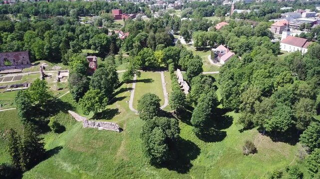 A scenic aerial panorama view of the historic medieval castle ruins and the modern Estonian Traditional Music Center on the green hills.