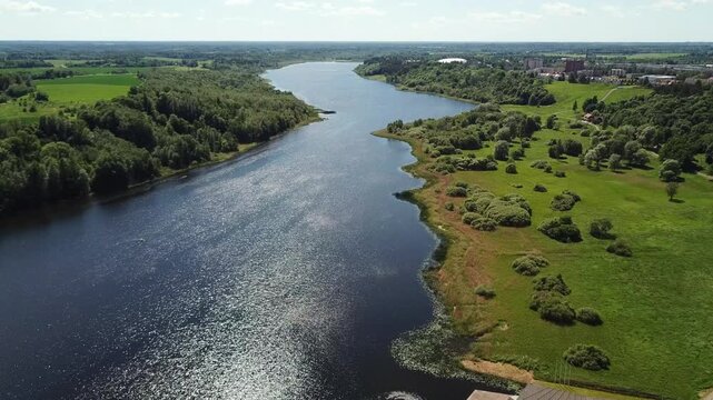 Cinematic aerial panorama showcasing the beautiful scenic view of Viljandi lake, sparkling water surface, and lush green summer forest landscape.