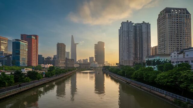 Beautiful sunrise timelapse over Ben Nghe canal and dynamic cityscape of Ho Chi Minh City with skyscrapers.