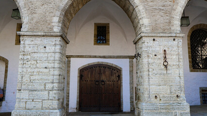 Fototapeta premium Tallinn Town Hall's historic entrance features ancient stone arches, an ornate wooden door, and a distinctive medieval architectural style reflecting old traditions and European heritage