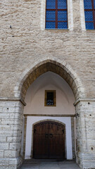 Naklejka premium Medieval wooden doors featuring iron rings and studded details, sheltered under a stone archway within a historic City Hall building in Tallinn's Old Town