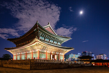 Fototapeta premium Majestic Geunjeongjeon Hall of Gyeongbokgung Palace at night under full moon and dramatic clouds in Seoul South Korea Buddhist style roof architecture