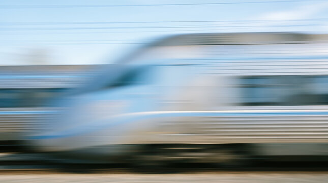 Abstract dynamic horizontal motion blur showing modern silver high speed passenger train rushing forward expressing rapid transport travel technology transit progress concept
