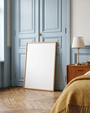 Blank wood frame mockup leaning on parquet floor next to pastel blue vintage wardrobe