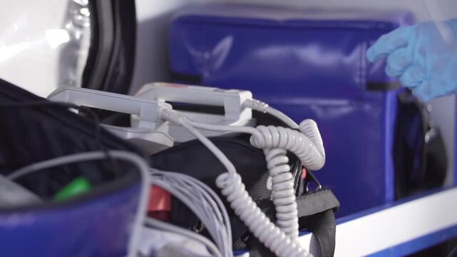 Emergency doctor hands reanimating man with defibrillator in ambulance car.