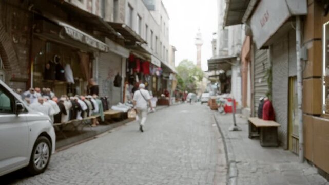 Istanbul street market scene rendered in soft defocused bokeh with cobblestone paving and shop facades; background backplate copyspace calm.