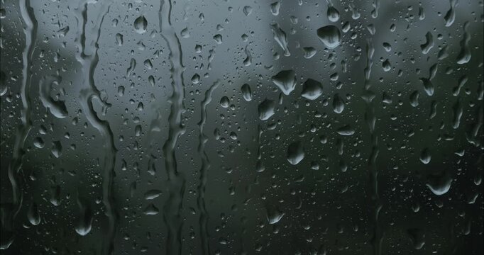 Heavy raindrops fall on the window glass. Thunderstorm and storm outside the window. Bad weather texture