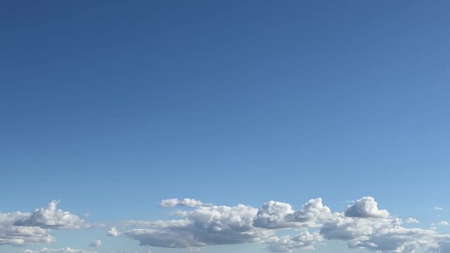 Fluffy clouds drifting across a clear blue sky