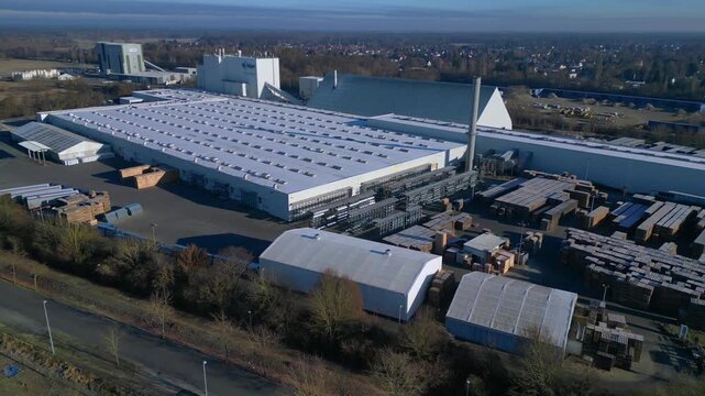 Large industrial complex manufacturing gypsum board, with extensive production facilities, material storage, and administrative buildings. Amazing aerial view