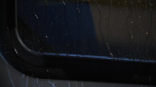 Rain water streaming down bus glass window in rainy weather with downpour.