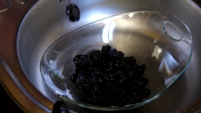 Washing dried prunes in glass bowl before cooking homemade recipe preparation process close up