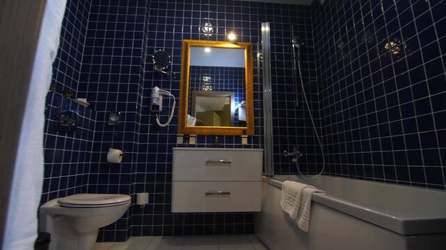 Modern bathroom with blue tile, toilet, bath, bidet, sink and wooden mirror.