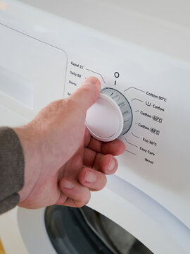 A man starts doing laundry in his washing machine at home.