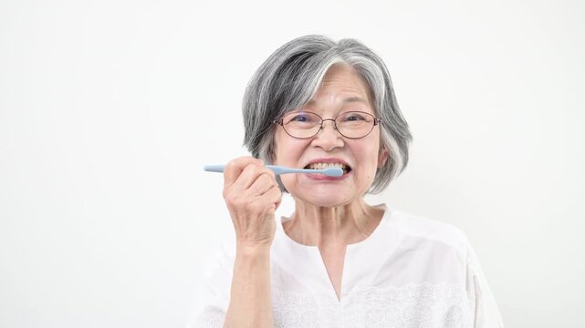  歯ブラシを持って歯磨きによる口腔ケアを行うシニア女性　8020運動のイメージの動画正面