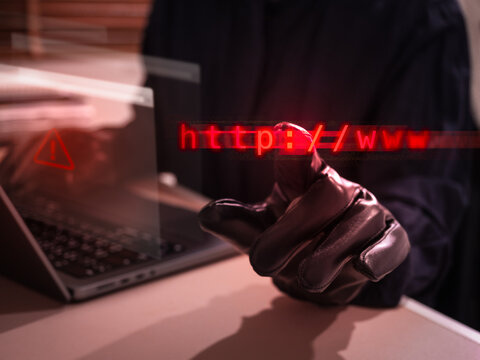 Cybercriminal with gloves creating fake website phishing scam with malicious web links and online fraud tactics. Cybersecurity threats, identity theft, data breach risks, and internet security danger.