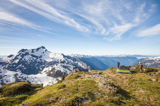 Two backpackers set up camp on a mountain ridge