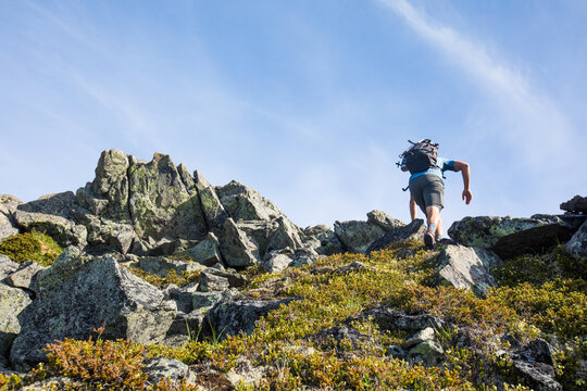 Hiker scrambles up a rocky mountain peak