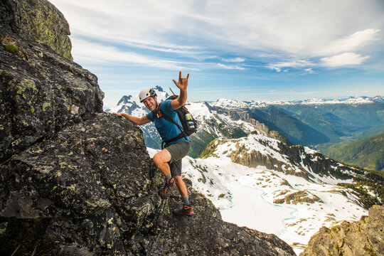 Happy hiker scrambles up a rocky mountain peak