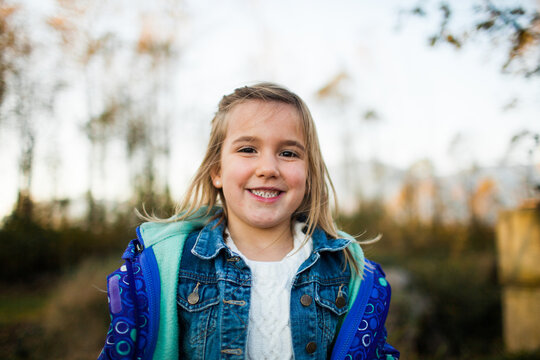 Happy young girl with backpack smiling outdoors